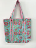 Floral patterned tote bag with pink and white striped handles on a light background