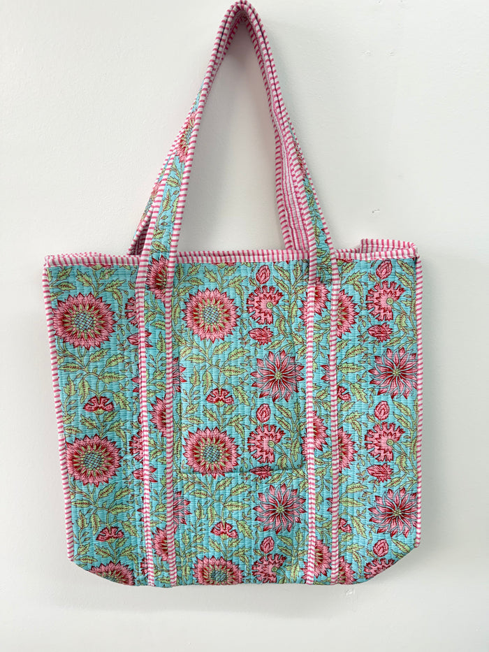 Floral patterned tote bag with pink and white striped handles on a light background