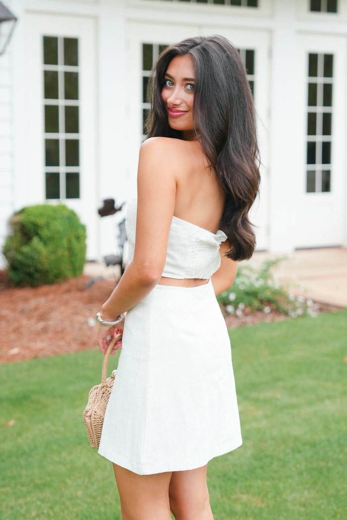 Woman in a white dress standing outdoors with a blurred background