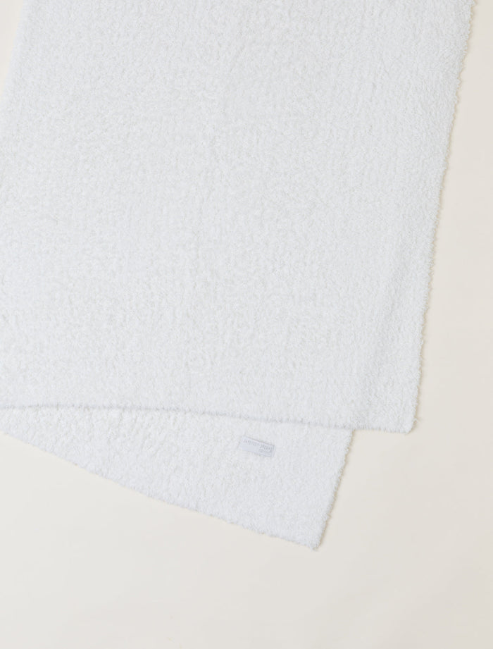 Close-up of a textured white fabric with a brand label on a beige background