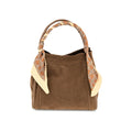 A brown suede handbag with a tan and cream patterned scarf tied to its handles, shown against a plain white background.