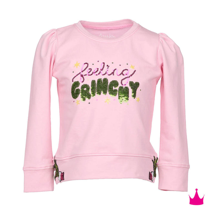 A pink long-sleeve sweatshirt for kids, featuring the phrase 'feeling GRINCHY' in glittery green and pink lettering with small star accents on the front. The sweatshirt has puffed sleeves, ribbed cuffs, and a small embroidered cactus detail near the hem.
