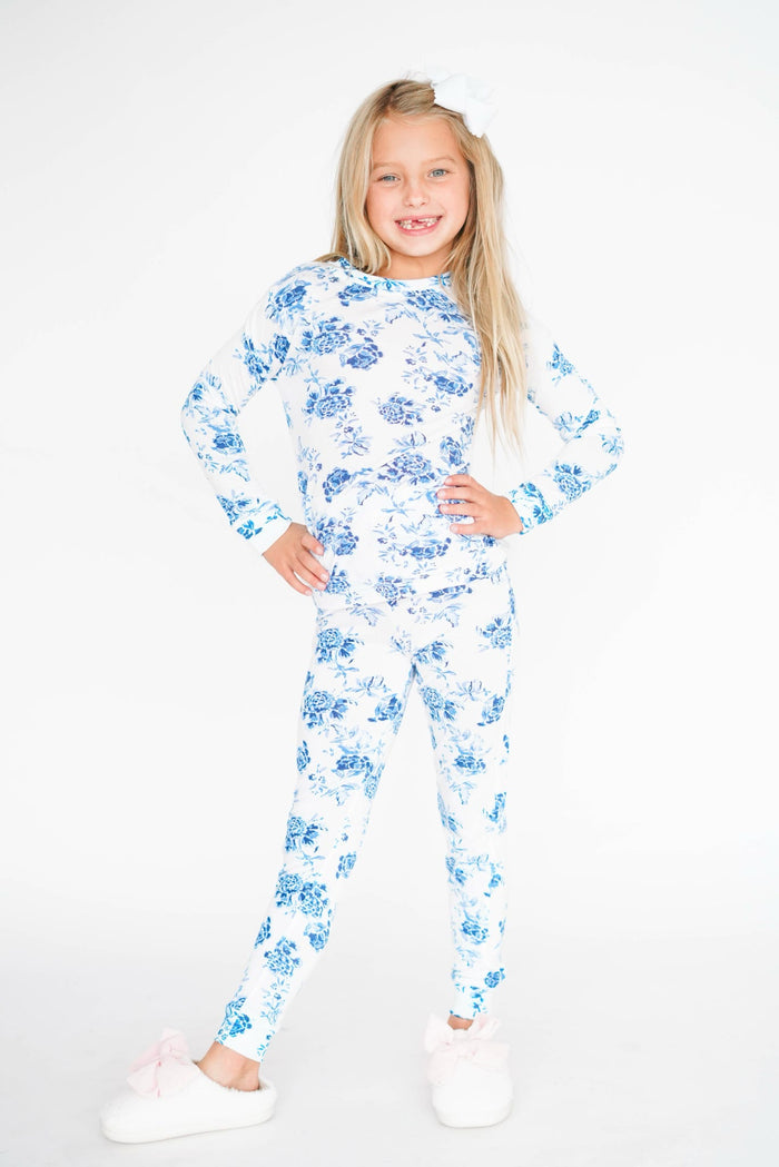 Young girl wearing a blue floral pajama set on a white background