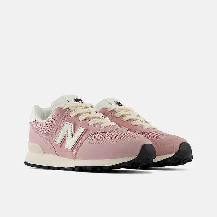 A pair of New Balance 574 sneakers in dusty pink with cream laces and a white 'N' logo, set against a light gray background.