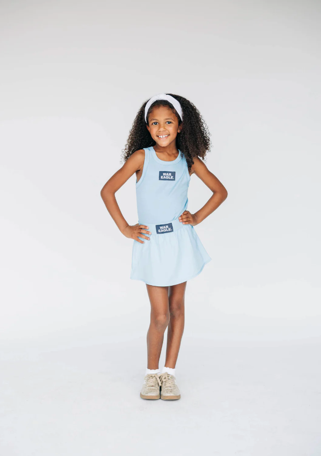 Young girl wearing a light blue dress with a brand logo on a white background