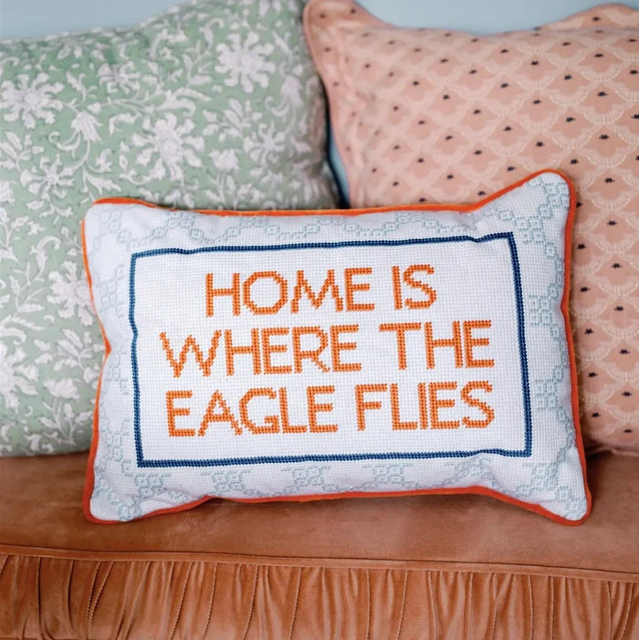 Decorative pillow with 'Home is where the eagle flies' text on a couch.