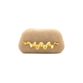 A beige suede clutch bag featuring a prominent, wavy, three-dimensional gold metal embellishment across the front, set against a plain white background.