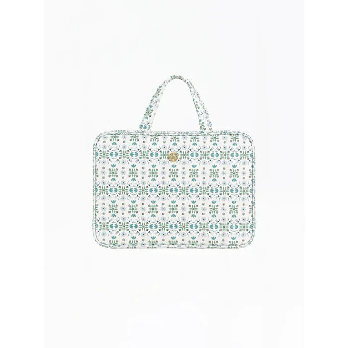 A laptop sleeve featuring a white background with a repeating teal and green geometric pattern, complete with two top handles and a small gold logo badge on the front.