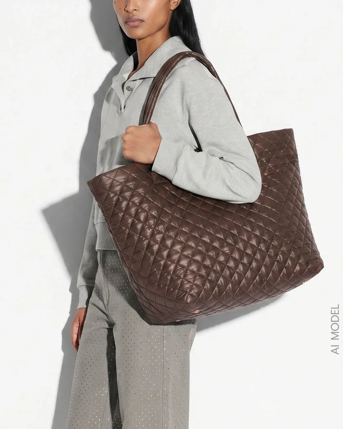 A model wearing a light gray sweatshirt and matching pants carries a large brown quilted leather tote bag against a white background with a strong shadow.