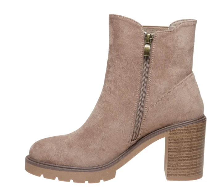 A taupe suede ankle boot with a chunky block heel, a side zipper, and a lug sole, shown against a plain white background.