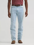 A person wearing light-wash blue jeans with a brown belt and brown shoes, shown from the waist down against a plain light gray studio background.
